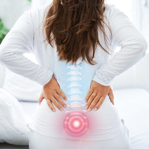 A woman holding her lower back, with a graphic showing the spine. The image highlights the lower back relief provided by the Back Magic back stretcher, with the spinal area visually emphasised.